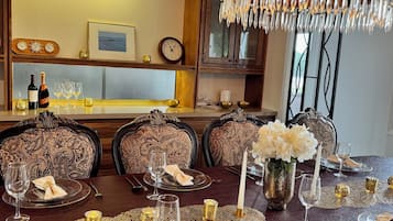 Un menjador formal amb cadires ornamentades, un penjant de llum i una taula posta per a dinar.