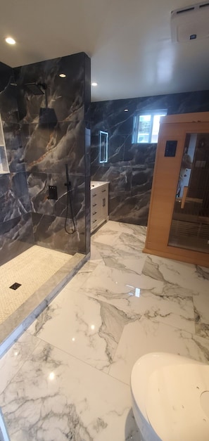 A bathroom with a shower, marble flooring, and a toilet.