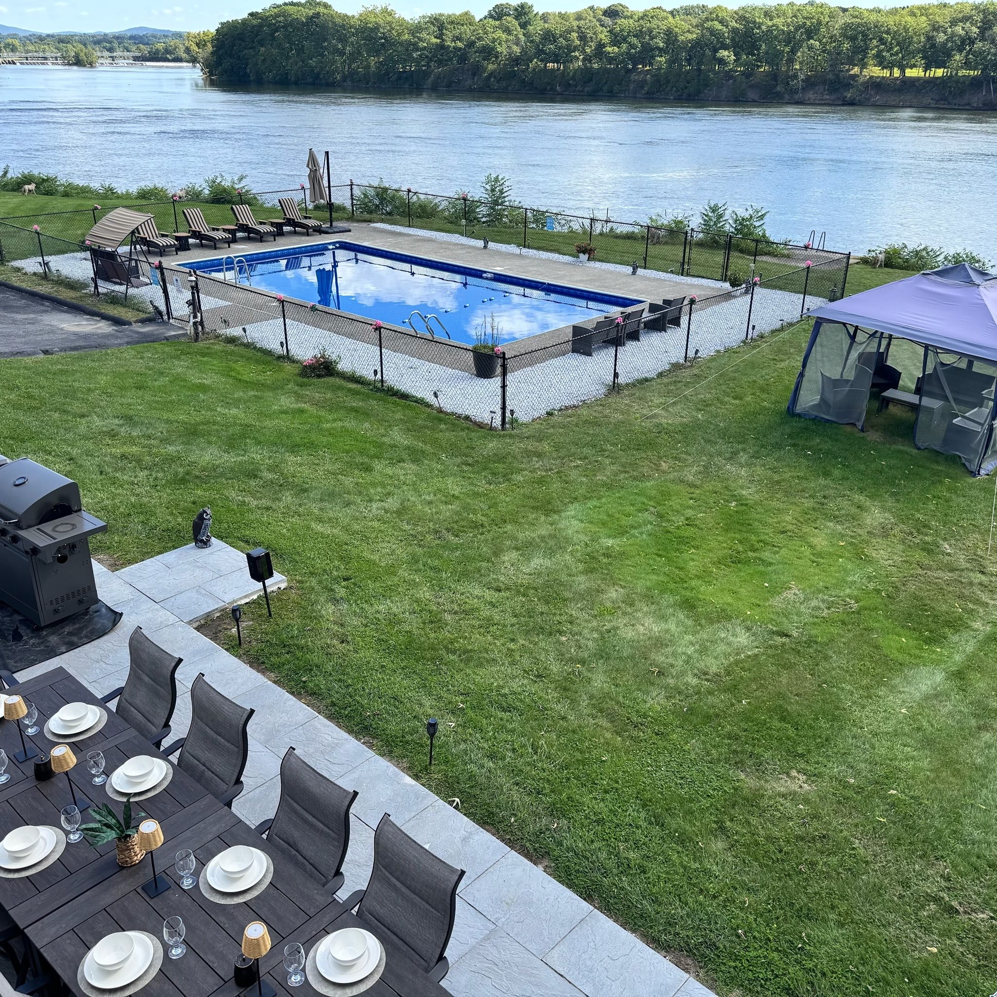 A swimming pool with lounge chairs, a covered seating area, and a dining setup with tables and chairs.