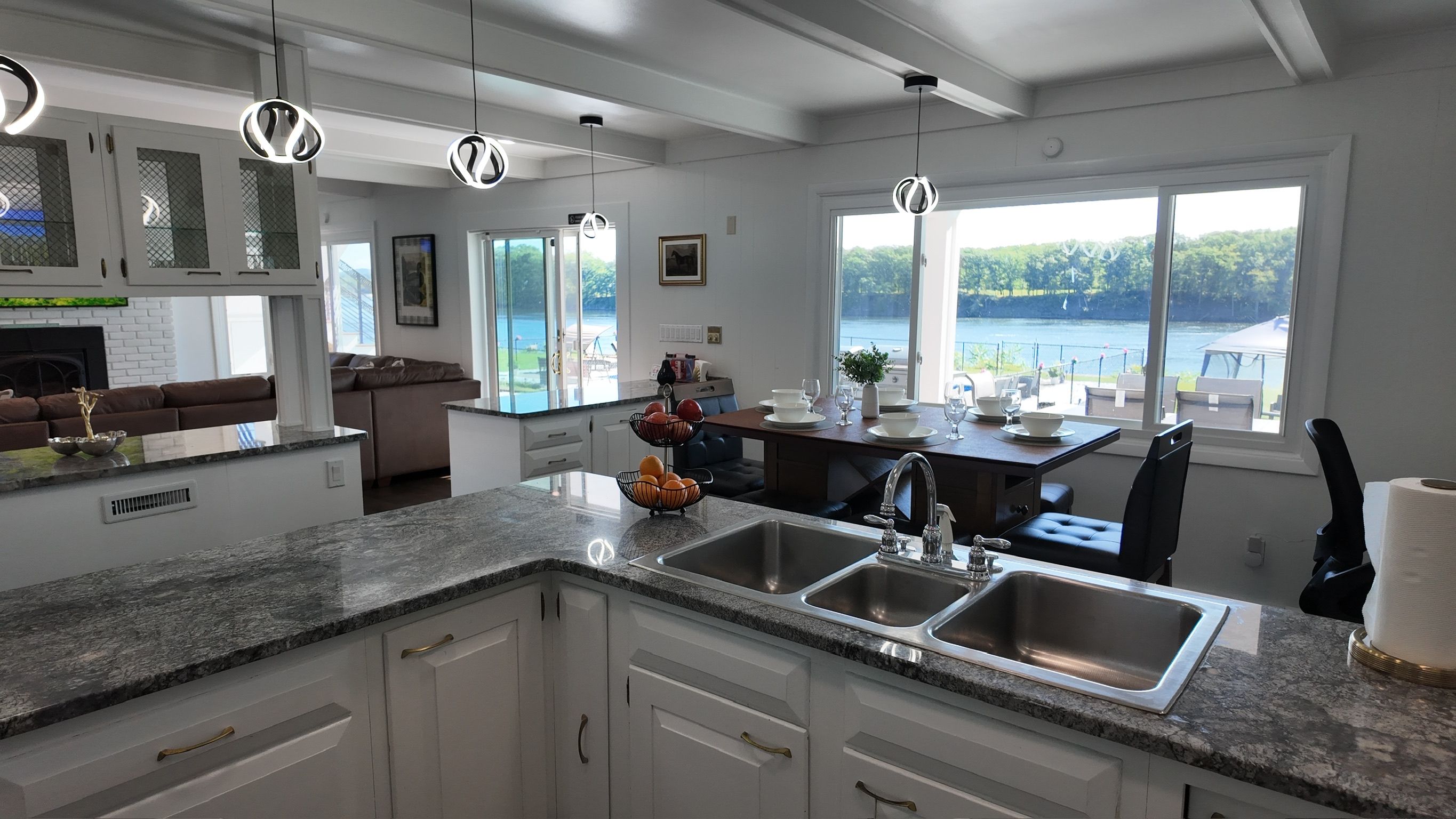 A modern kitchen with granite countertops, stainless steel appliances, and a view of a lake.