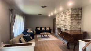 A living room with a stone fireplace, a piano, a sofa, and a coffee table.