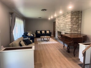 Una sala de estar con chimenea de piedra, un piano, un sofá y una mesa de centro.