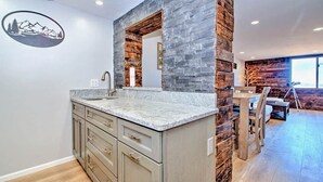 Una cocina moderna con encimera de granito, detalles de madera y un adhesivo mural con temática de montaña.