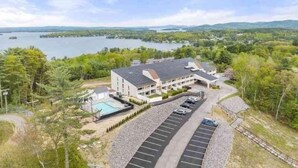 Un hotel moderno con piscina, estacionamiento y vistas panorámicas a un lago.