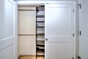A white closet with multiple shelves and hanging space. - Adorable Cedar Lodge Room w/ Lake Views! (Laconia)