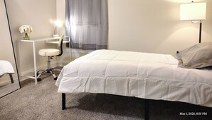A hotel room with a bed, a desk, a chair, a lamp, and a window with curtains. - Charming 3-bedroom house in peaceful Binghamton, close to downtown, with ACs (Binghamton)