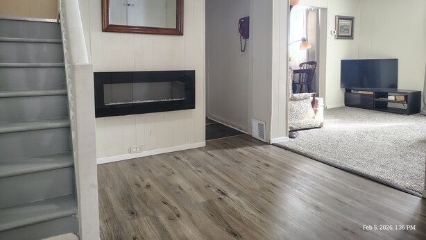 A living room with a fireplace, a television, and a staircase. - Charming 3-bedroom house in peaceful Binghamton, close to downtown, with ACs (Binghamton)