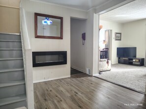 Ein Wohnzimmer mit Kamin, Fernseher und Treppe.