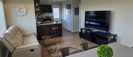 Een moderne woonkamer met een bank, een eettafel, een televisie en een keuken met een bar.