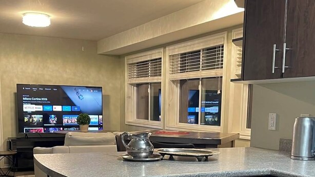 A modern kitchen with a built-in dishwasher, dark wooden cabinets, and a large island with a kettle. - Mountain House: An apartment with a gorgeous ocean view on Triangle Mountain. (Victoria)