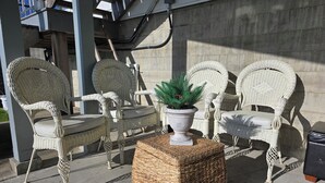 Wicker furniture with cushioned seats and backs, a potted plant, and a woven ottoman. - Mountain House: An apartment with a gorgeous ocean view on Triangle Mountain. (Victoria)