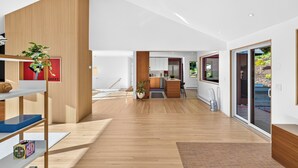 A spacious interior with a wooden floor, a kitchen area, and a large sliding glass door leading to an outdoor area. - Dartmouth Graduation—Luxury MCM Home in Hanover (Hanover)