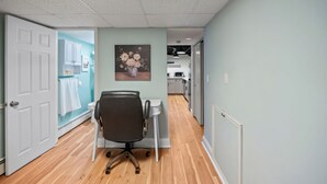 A hallway with a white door, a black office chair, a white table, and a painting of flowers on the wall. - Cozy in Canton - Private Driveway - Pet Friendly (Baltimore)