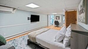 A hotel room with a bed, a TV mounted on the wall, a desk, and a chair. - Cozy in Canton - Private Driveway - Pet Friendly (Baltimore)