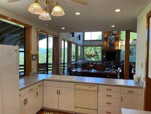 A kitchen with a large island, wooden cabinets, and a dining area with a stone fireplace. - Jaw dropping Mtn View, close to all attractions, plenty of room for families, huge porch, game room in garage , birds galore, great kitchen, watch sunsets, (Bryson City)