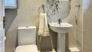 A small bathroom with a toilet, sink, and a towel hanging on a rack. - Kent Retreat Book Today and Relax (Gravesend)