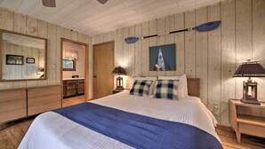 Una camera da letto con un letto grande, pareti in legno, una ventola a soffitto, un quadro e un comodino con una lampada.