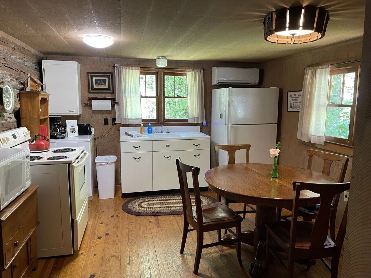 Una cocina compacta con una mesa de comedor, armarios de madera, un refrigerador y un microondas.