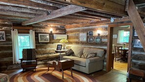 Un interior acogedor de cabaña de madera con un sofá, un sillón y una alfombra estampada.