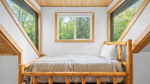 A room with a wooden bed, a window, and a sloped ceiling. - Hidden Wears Valley Family Retreat, Hot Tub, Pets (Sevierville)