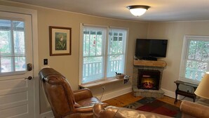A living room with a fireplace, leather chairs, a television, and a window with blinds. - Private fire pit, creek: Bryson city (Bryson City)