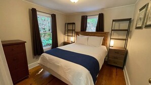 A bedroom with a wooden bed, a dresser, a nightstand, and a window with curtains. - Private fire pit, creek: Bryson city (Bryson City)