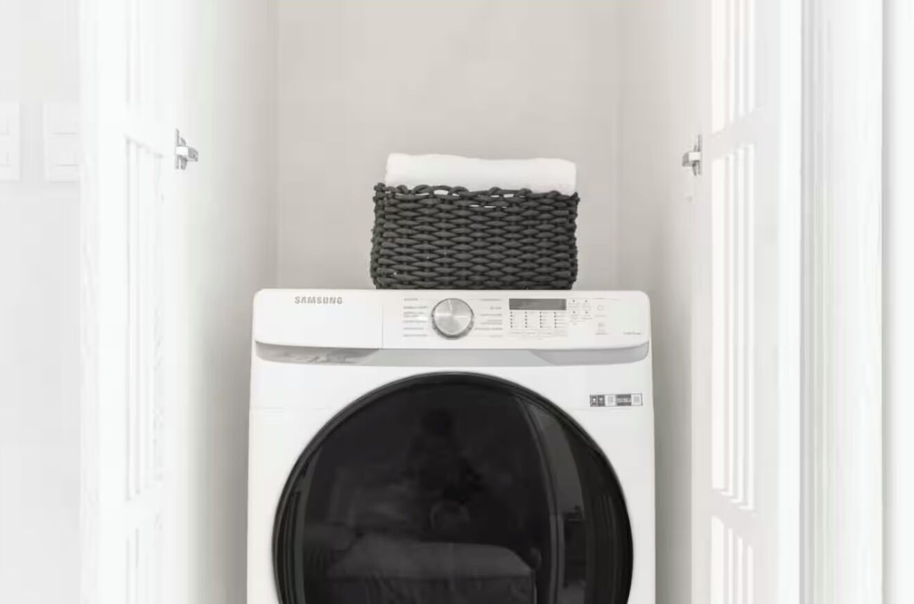 A Samsung washing machine in a laundry room with a basket on top.