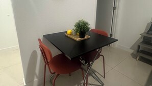 Ruokailutila, jossa on musta pöytä, punaiset tuolit ja ruukussa oleva kasvi pöydällä.