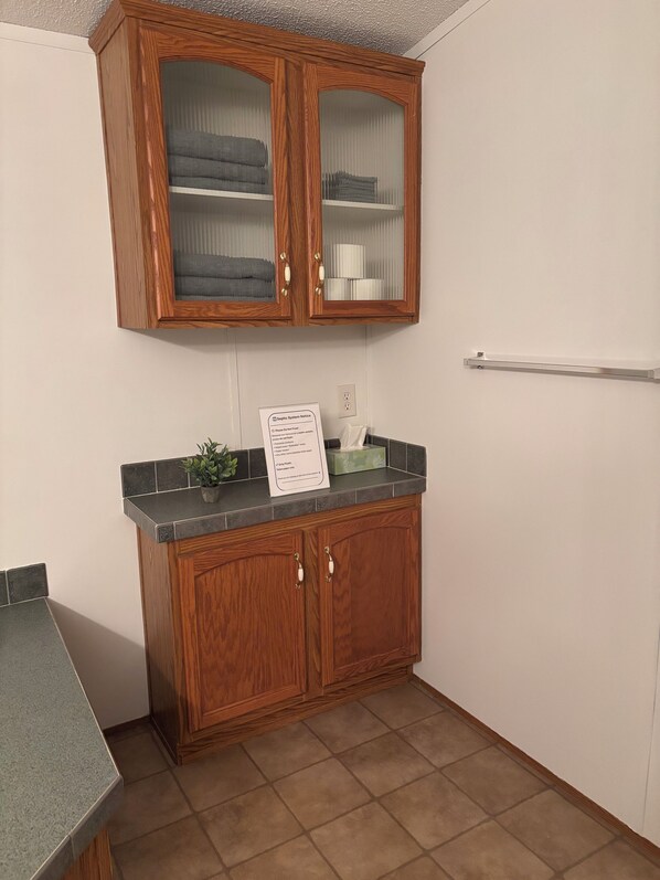 A kitchen with wooden cabinets, a countertop, and a sign indicating a septic system notice. - Amazing 3-bedroom house in Plymouth perfect for your getaway (Plymouth)