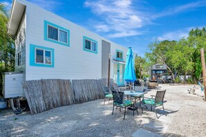 A mobile home with a patio area, outdoor furniture, and a blue umbrella. - Tiny House Paradise - Pool, Spa, Slide, Beaches (Bradenton)