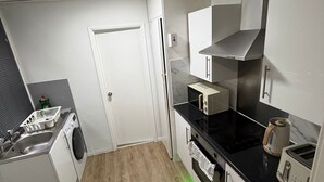 A compact kitchen with a washing machine, a stove, and a toaster. - Amazing Garden Apartment - Miami Lodge (Reading)