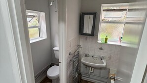 A compact bathroom with a toilet, sink, and window. - Amazing Garden Apartment - Miami Lodge (Reading)