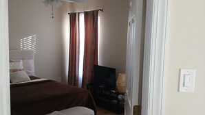 Une chambre à coucher comprenant un lit, une table de chevet, un téléviseur et un ventilateur de plafond.