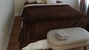 Une chambre à coucher avec un lit, une table de chevet, un ventilateur de plafond et une fenêtre avec des rideaux.
