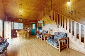 A wooden cabin interior with a staircase, a dining area, and a sofa. - Cozy Family Friendly Green Cabin Unit A (Warrens)