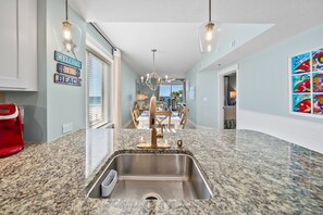 Eine Küche mit Granit-Arbeitsplatte, Edelstahl-Spüle und Pendelleuchten.