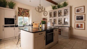 Een moderne keuken met een centraal eiland, witte kastjes en een kroonluchter.