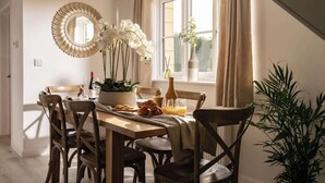 Un coin repas avec une table en bois, des chaises et un vase rempli de fleurs blanches.