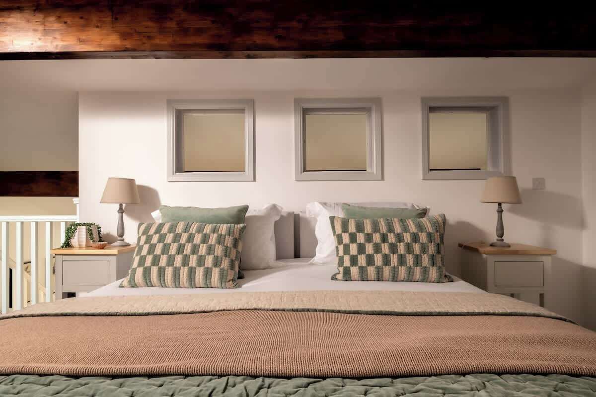 Une chambre à coucher bien rangée, avec un grand lit, deux tables de chevet et trois tableaux encadrés accrochés au mur.