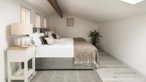 A bedroom with a skylight, a bed with pillows, a bedside table, and a plant. - Goodwood - Modern Stay in Cotswolds with Hot Tub (South Cerney)