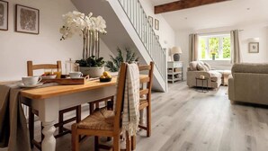 Una sala moderna con una mesa de comedor de madera, un sofá y una escalera.