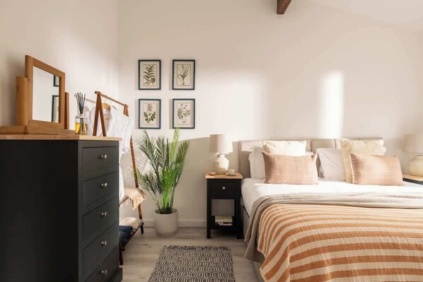 A bedroom with a bed, dresser, nightstand, and wall art. - Epsom - Cosy Stay in the Cotswolds (Gloucestershire)