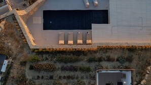 An aerial view of a modern house with a swimming pool, a covered patio, and a garden area. - Villa Arcadia (Naxos)