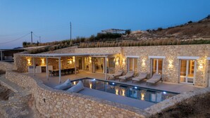 A stone house with a swimming pool, outdoor seating, and a covered patio area. - Villa Arcadia (Naxos)