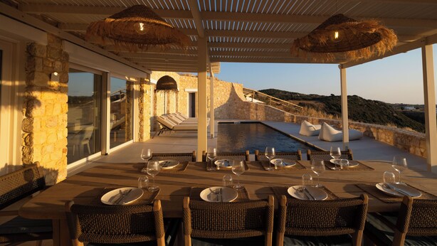 An outdoor dining area with a table set for six, overlooking a pool and a mountainous landscape. - Villa Arcadia (Naxos)