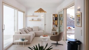 A modern living room with a sofa, a coffee table, a chair, and a bookshelf. - Villa Arcadia (Naxos)