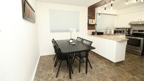 A modern kitchen with white cabinets, a black dining table, and a built-in island. - Cozy 3 bedroom home close to all amenities (Winnipeg)
