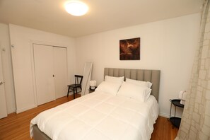 A bedroom with a bed, a chair, a nightstand, a painting, and a door. - Cozy 3 bedroom home close to all amenities (Winnipeg)