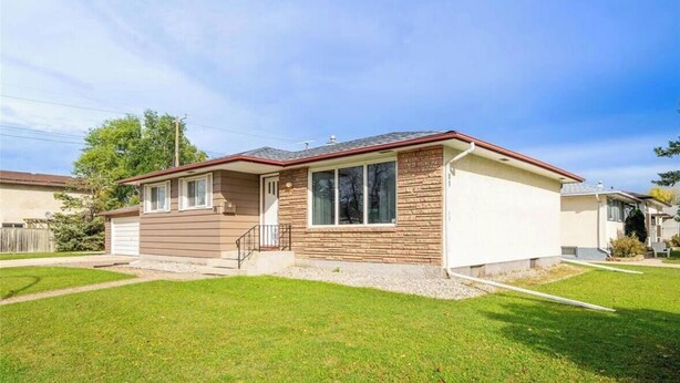 A single-story house with a front porch, a garage, and a well-maintained lawn. - Cozy 3 bedroom home close to all amenities (Winnipeg)