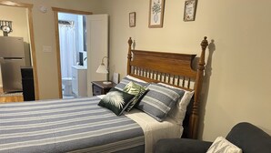 A bedroom with a bed, a wooden headboard, a bedside table, a lamp, and a chair.